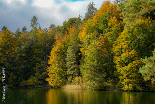 Autumnal atmosphere and colorful trees at Lake Hechtsee, a popular swimming lake in the Brandenberg Alps near Kufstein in Tyrol, Austria