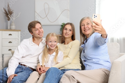 Senior woman taking selfie with her son's family at home