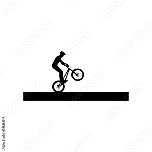 Silhouette of a person performing a bicycle stunt on a flat surface.
