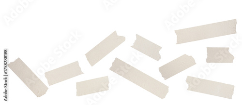 photograph of small, scattered pieces of beige masking tape arranged irregularly, showcasing ripped edges and realistic paper texture, isolated on black.