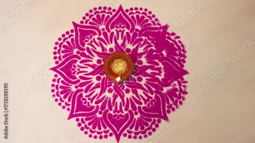 Top view of clay oil lamp or diwali diya with pink color rangoli design on white background. Selective focus.