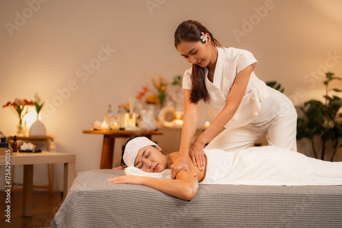 Fotografie Asian masseuse provides therapeutic back massage for adult client in tranquil sp
