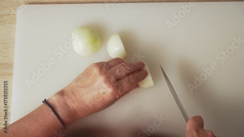 Watch as an individual skillfully chops onions on a clean cutting board in a warm