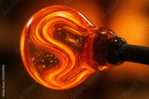 Glowing Molten Orange Glass Bulb with Swirling Patterns on Blowpipe Against Warm Fiery Background