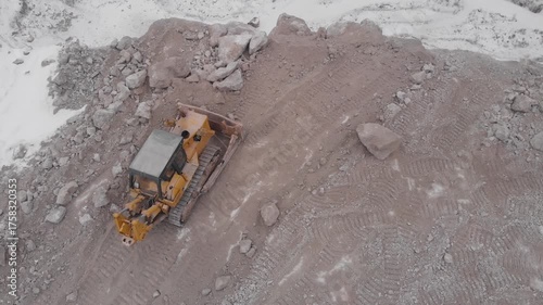 A tractor throws rocks off a cliff.