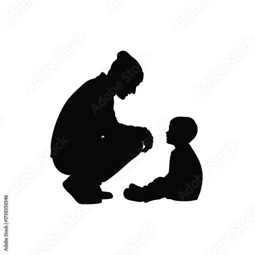 Silhouette of a man in a beanie crouching down and looking at a small child sitting down