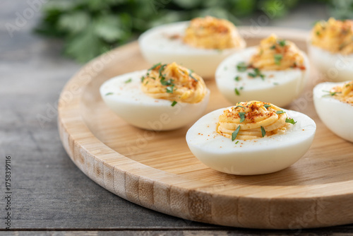 Homemade hard Boiled Deviled Eggs garnished with herbs on wooden table