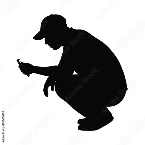 Silhouette of a person in a crouching position looking at a small object in their hand closely