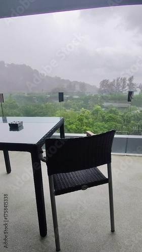 Black table and chairs on the balcony in the rain