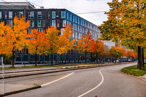Modern Office Building With Autumn Garden Pathway in Munich Hackerbruecke: Contemporary Glass Architecture Surrounded By Colorful Trees And Soft Evening Lights In Urban Setting