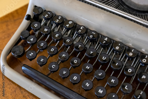 Vintage typewriter keyboard with round black keys, qwerty layout and shiny keytops on old writing machine, retro journalism and literature concept, close up detail of mechanical letters numbers levers