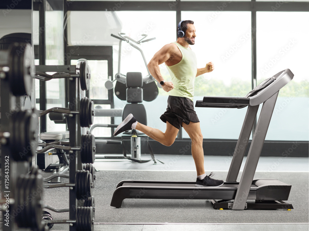 Fototapeta premium Full length shot of a man at a gym running on a treadmill