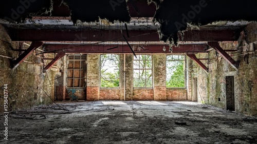 Derelict warehouse, dark abandoned industrial factory building interior. Darkness shadows, bright sunlight through broken windows. Collapsing ceiling insulation metal girders roof beams. Daylight ruin