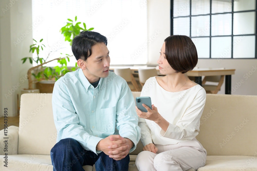 Fototapeta premium ソファに座ってスマホを見る日本人男女