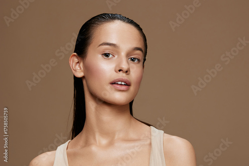 Fotografi Young woman with dewy skin and natural makeup, wearing a beige top against a war