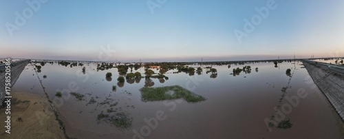 A 180 degrees aerial panorama of a flooded village and its surrounding agricultural land 