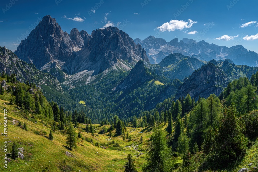 Fototapeta premium Majestic mountain peaks towering over lush green slopes with a serene landscape of grassy patches and dense coniferous trees under a clear blue sky, evoking tranquility in nature's beauty