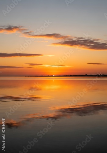 Serene sunset over calm waters reflects the vibrant sky in a mesmerizing scenic landscape