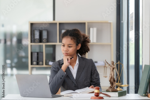 An American woman is a legal litigation attorney. A female lawyer is in a law firm, drafting contracts and reviewing client case details to study and find a solution to win the case.