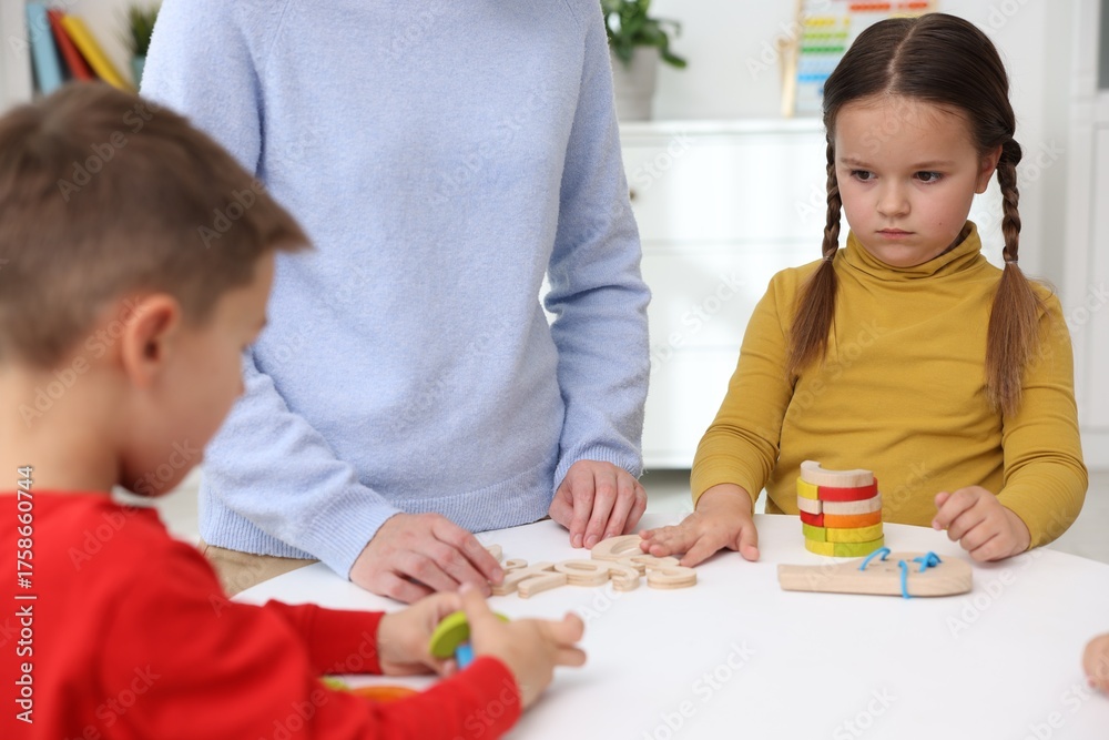 Fototapeta premium Cute children and teacher at white table during lesson in elementary school, closeup