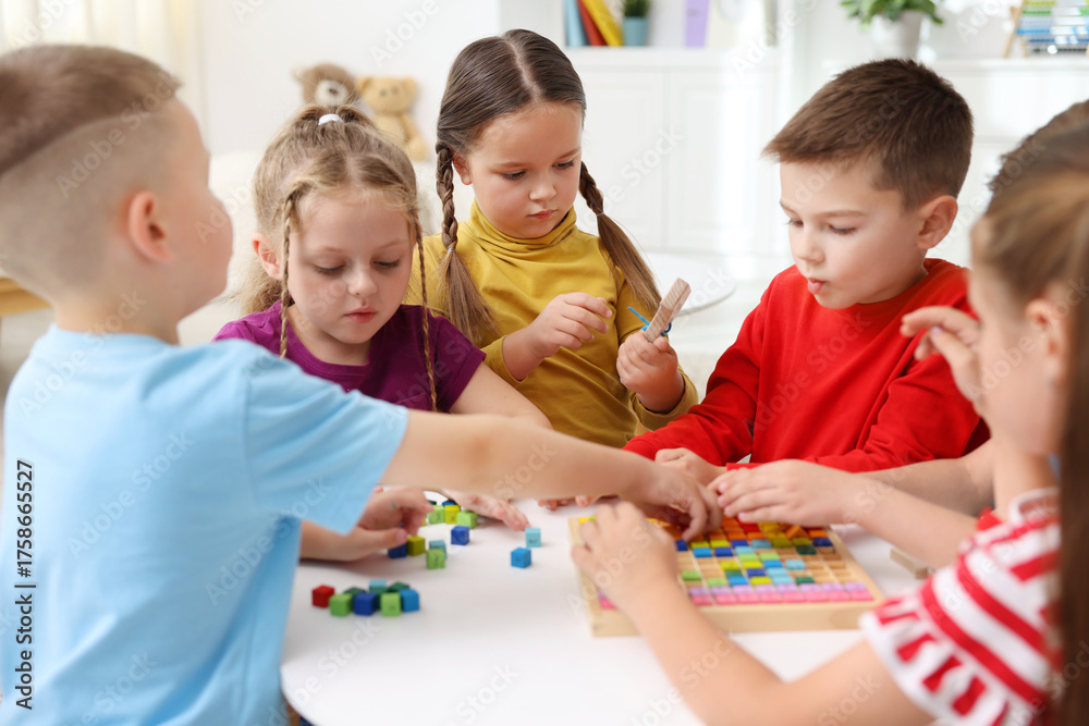 Fototapeta premium Cute children at white table during lesson in elementary school