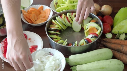 Assembling a Traditional French vegetable ratatouille casserole. Harvest festival, seasonal vegetables, autumn dish. Onions, zucchini, eggplant, tomatoes, peppers arranged circle. Vegan french tian 4K