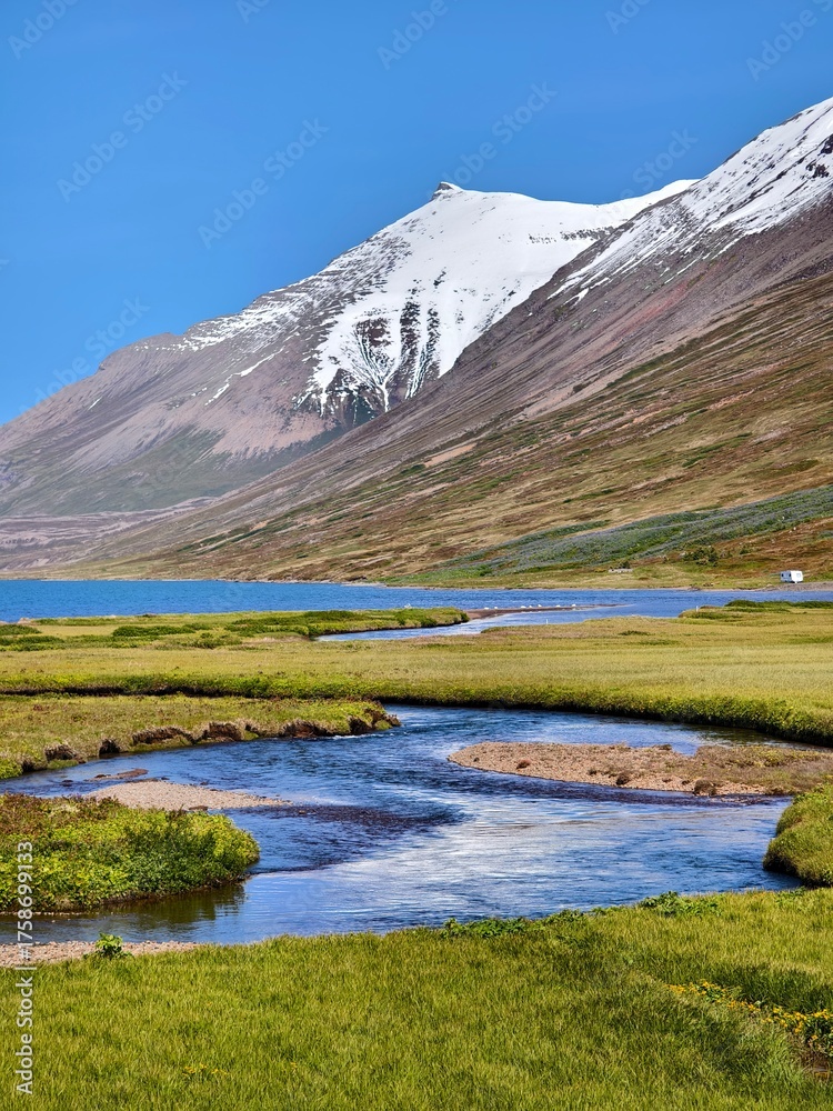 Fototapeta premium Snow-capped mountain peaks, green meadows and blue river surface in Iceland