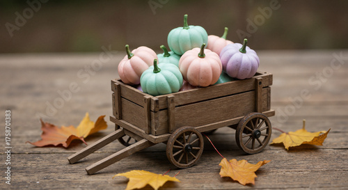 Colorful pumpkins in wooden cart on rustic table with autumn leaves  