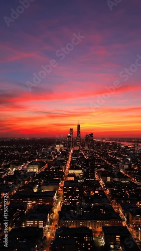 Skyscrapers silhouetted against a vibrant orange and purple sunset sky