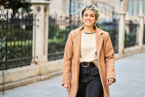 Young woman walking and smiling on city street