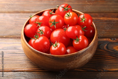 Fresh ripe tomatoes in bowl on wooden table, closeup