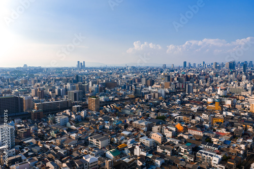 Photography Aerial view of Osaka, Japan shows low and mid rise housing in foreground, modern high rises and skyscrapers downtown, rail lines and roads, late afternoon light, wide angle depth