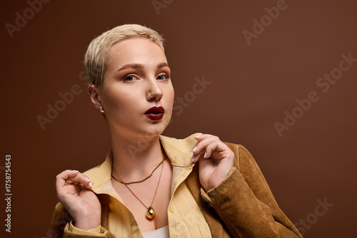 Photos Fashionable young woman showcasing a stunning look against a warm, neutral backd