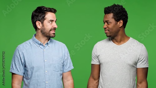 Two men on a green background. One in blue, the other in gray, facing each other, gesturing