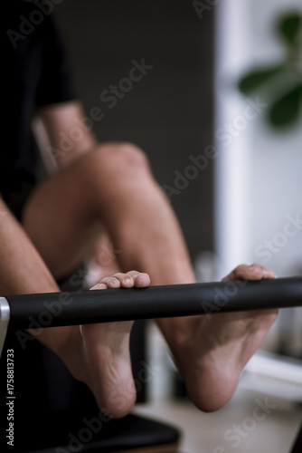 Engaging in reformer pilates workout focusing on foot and leg strength with specialized equipment in a modern studio setting