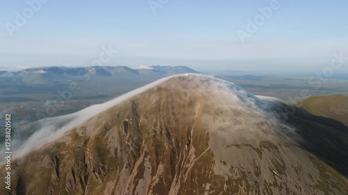 Amazing 4K aerial video of flying above and around Most Famous mountain in Ireland - Croagh Patrick in windy weather, with moving fog and clouds with breathtaking views around, Westport, Ireland