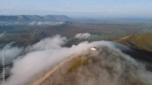 Amazing 4K aerial video of flying above and around Most Famous mountain in Ireland - Croagh Patrick in windy weather, with moving fog and clouds with breathtaking views around, Westport, Ireland