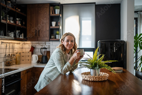 Woman enjoying morning coffee in modern kitchen