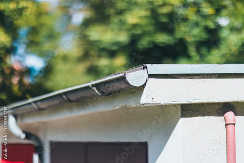 Rain Gutter and Downspout on House Roof, Sunny Day