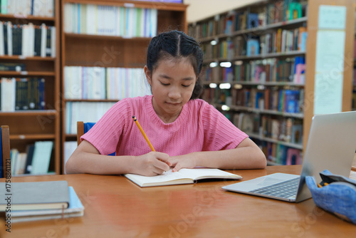 Student learning online class by using laptop computer and writing notebook at workplace, E learning and online working concept.
