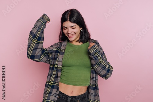 Young woman celebrating with a joyful expression against a pink background