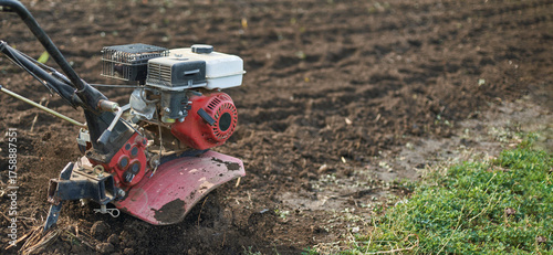 Obraz na plátně Red and white tiller on agricultural field for efficient soil cultivation-landscaping equipment on freshly plowed earth