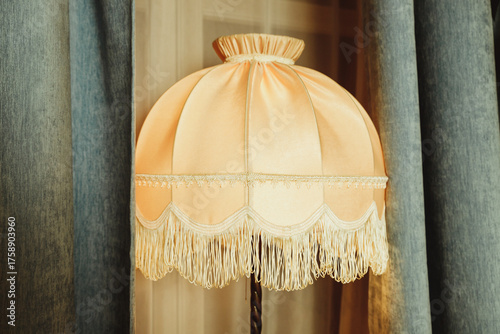 beautiful Lampshade in bedroom.old floor lamp with a hole with a fringe.Room decoration in retro style, furniture details and old lamps by the window.Vintage floor lamp