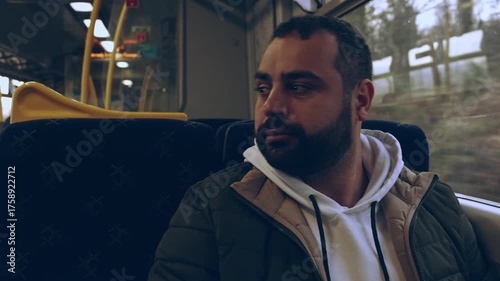Cinematic view inside a moving train carriage with travelers and warm sunlight streaming through the window. The screen shows upcoming stops. Peaceful travel atmosphere, perfect for lifestyle