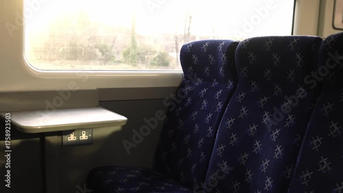 Cinematic view inside a moving train carriage with empty seats and warm sunlight streaming through the window. The screen shows upcoming stops. Peaceful travel atmosphere, perfect for lifestyle and jo