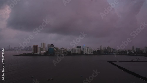 A day to night time lapse of the clouds passing over the city skyline or urban landscape of Mumbai, India, next to the Arabian Sea in the monsoon or rainy season. 