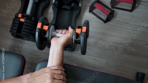Athletic man lifting adjustable dumbbell at home