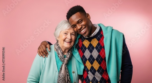 African young male and caucasian elderly female smiling together on pink background