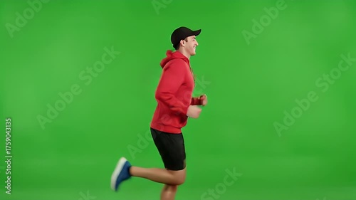 Man running on green screen wearing red hoodie and black shorts.