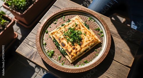 A delicious Turkish gozleme filled with spinach and cheese on a rustic wooden table